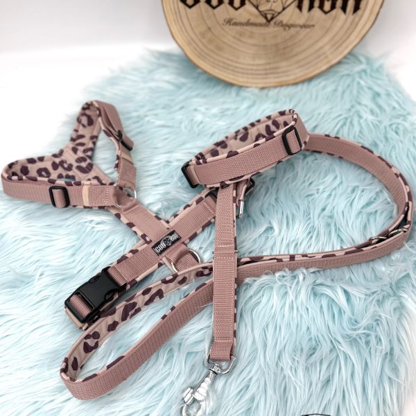 Handgemachtes Hundegeschirr mit passender Leine in Taupe mit Leopardenmuster, gepolstert mit Softshell, schwarzer Hardware und Coorox-Label – präsentiert auf hellblauem Kunstfell mit Holzlogo im Hintergrund.“